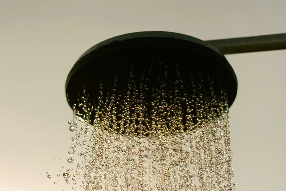 Pomme de douche en fonctionnement, gouttes en contre-jour