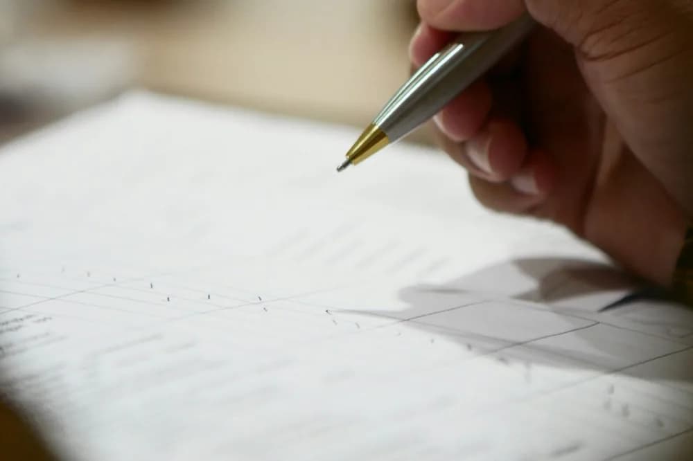 Main tenant un stylo au-dessus d'un document réglé