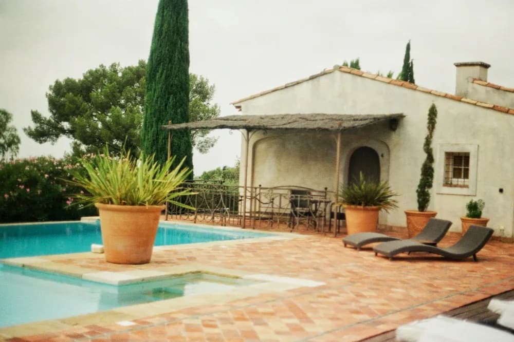 Bassin bordé d'une terrasse en terre cuite devant une maison de campagne