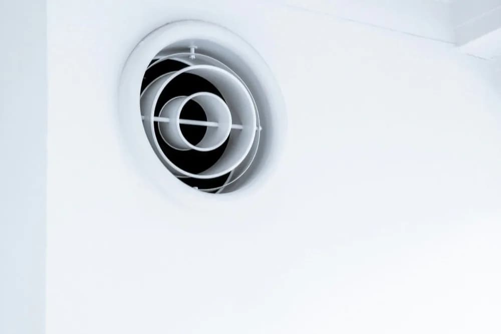 Bouche d'aération ronde encastrée dans un plafond blanc